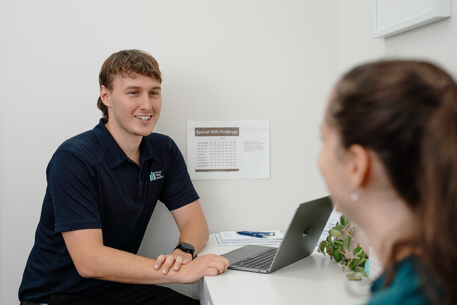 Jarred smiling across the desk at a patient, laptop open between them