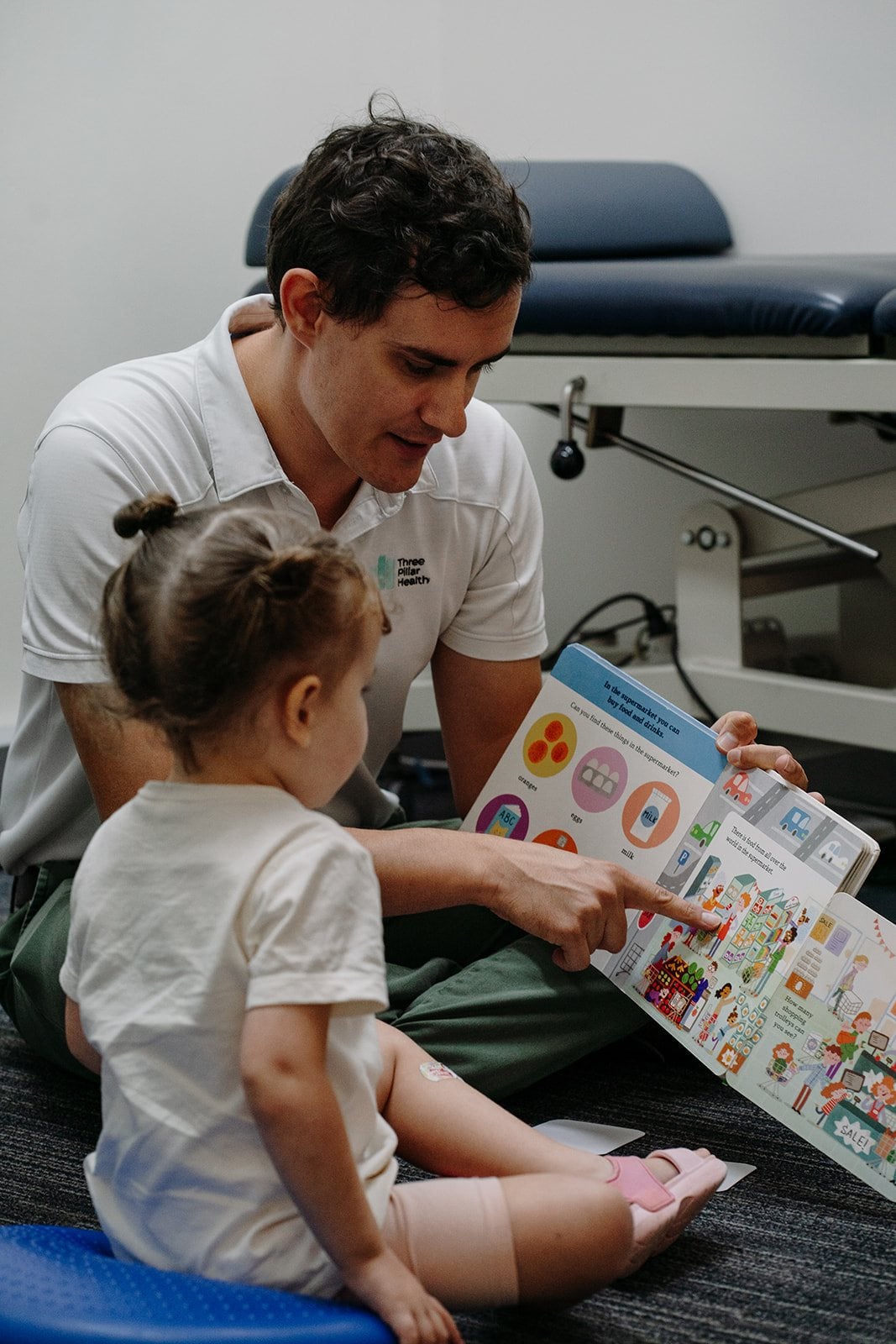 Speech pathologist Jonathon Cronk pointing at a picture book with a young child