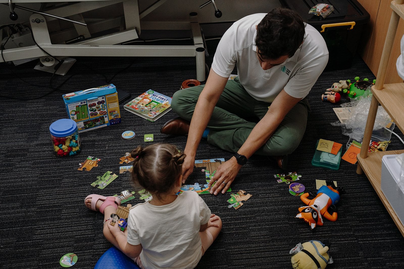 Speech pathologist Jonathon Cronk and a child doing a floor puzzle together
