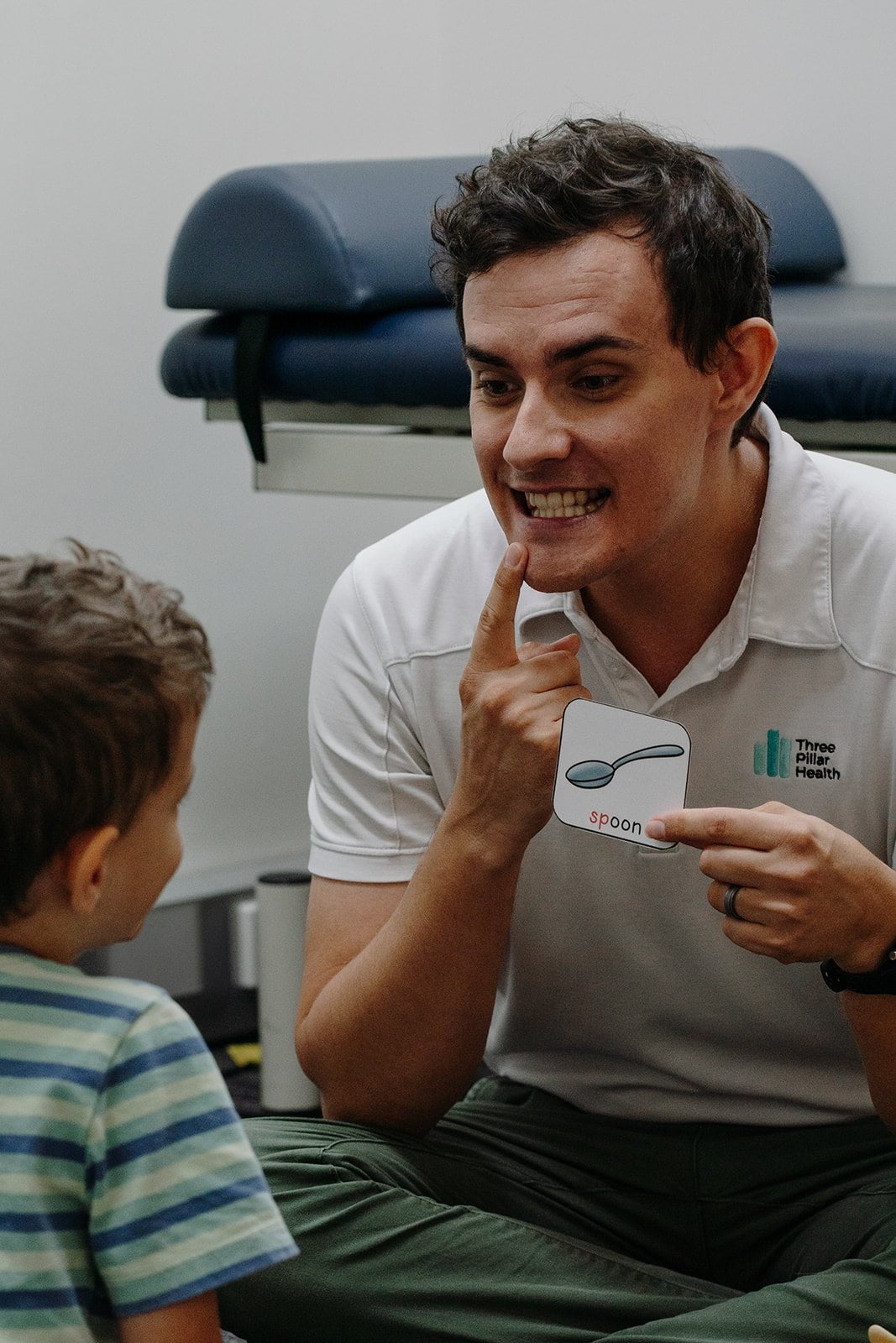 Speech pathologist Jonathon Cronk showing a child how a sound is made, picture card in hand
