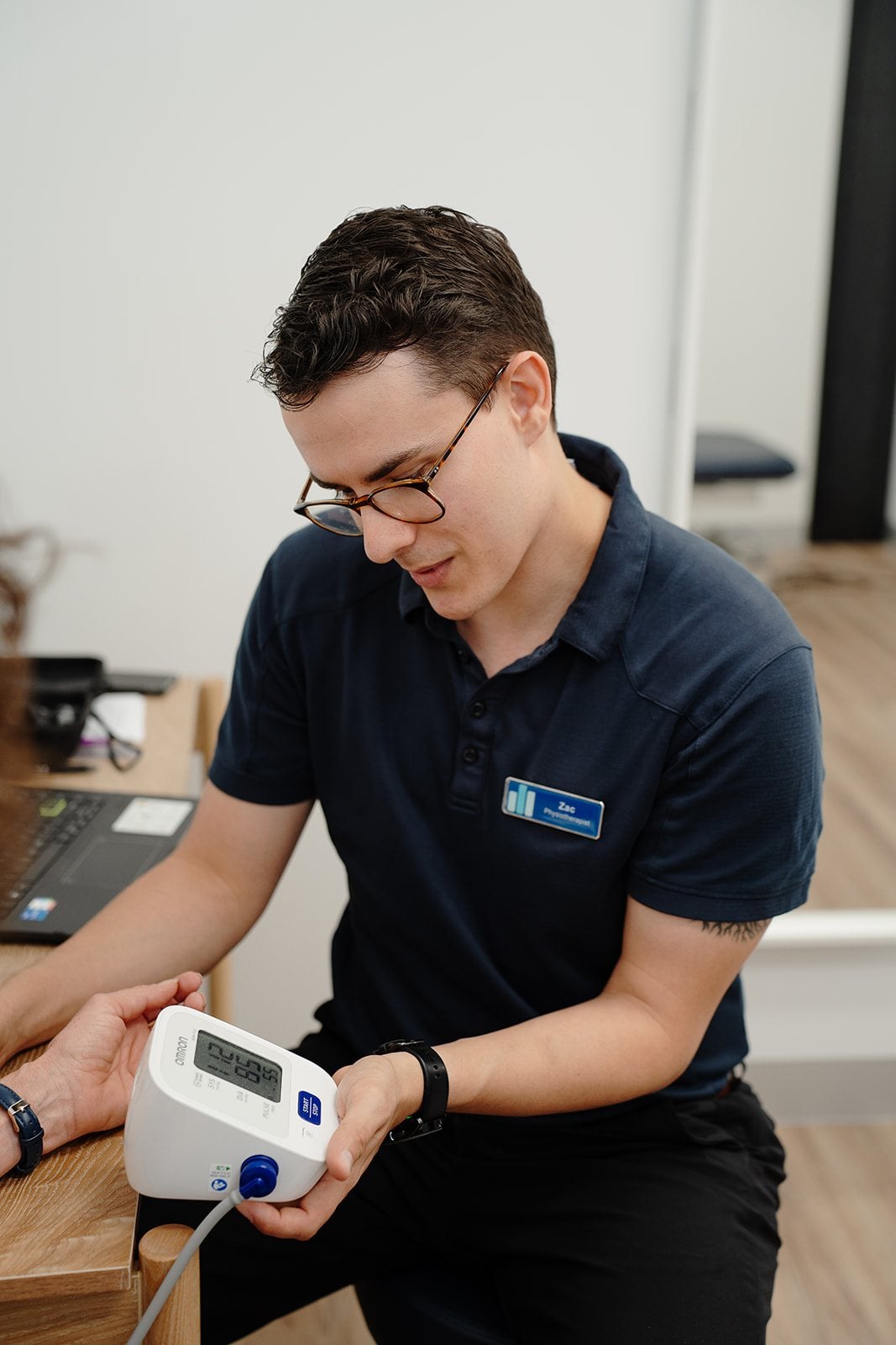 Physiotherapist Zac Cronk taking a patient's observations at the desk
