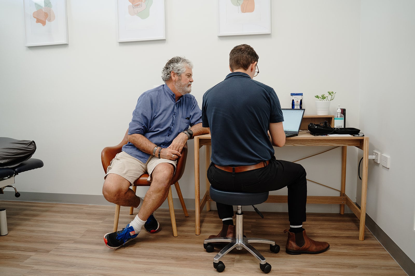Zac and a patient at the desk, seen from the doorway