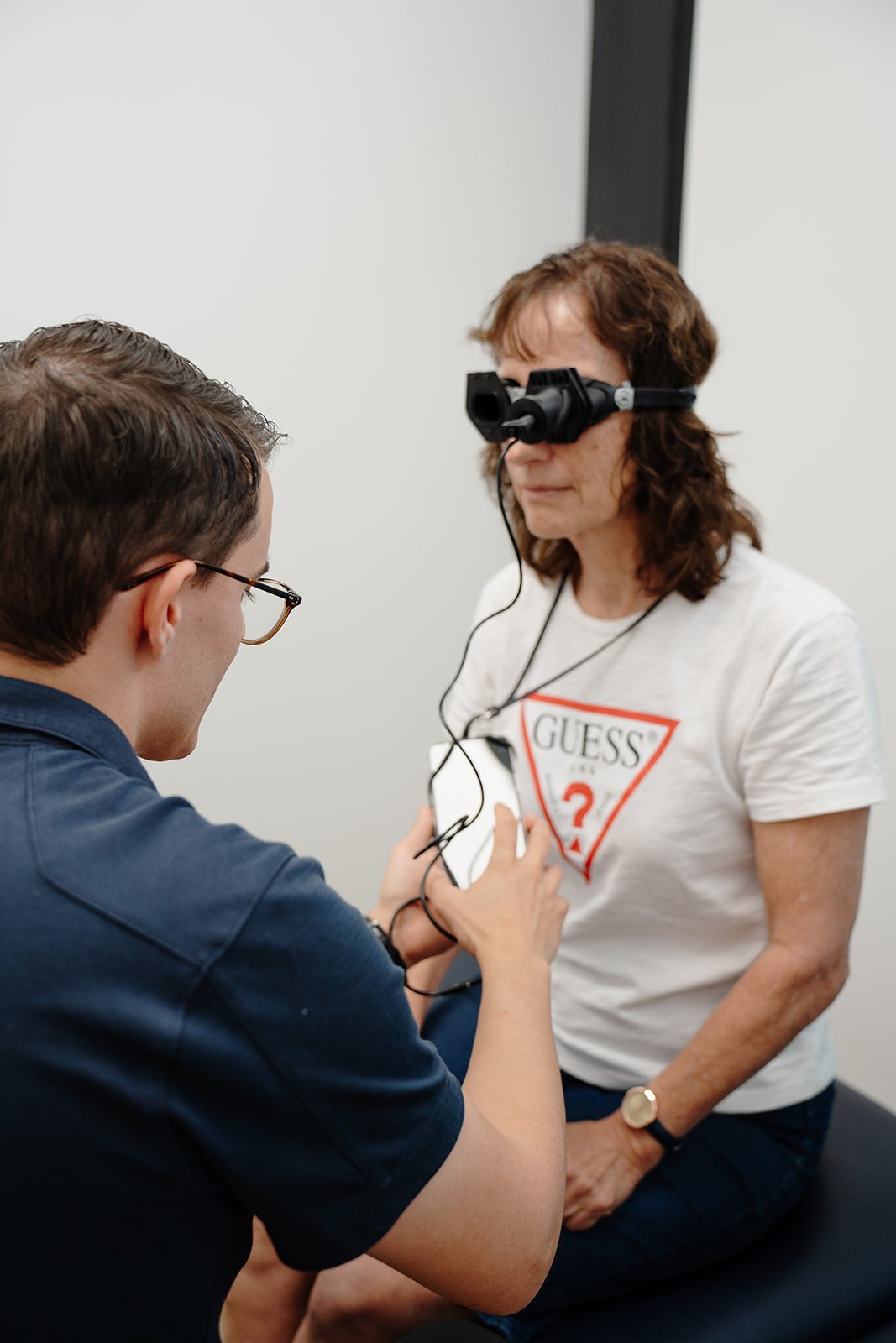 Physiotherapist Zac Cronk fitting vision-denied Vesticam goggles on a patient before a vestibular assessment