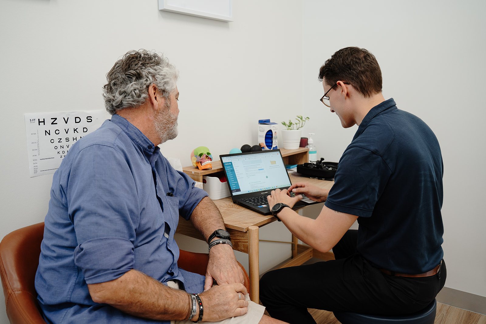 Physiotherapist Zac Cronk talking a patient through his management plan on the laptop